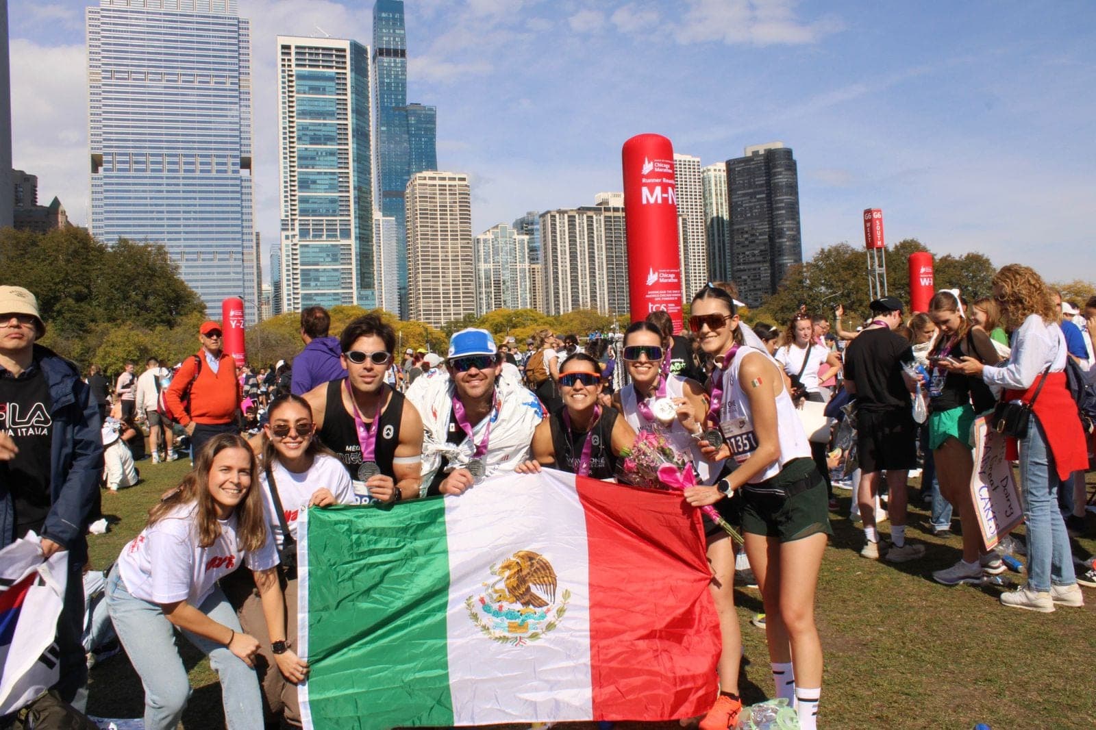 Wave One marathon finishers holding a Mexican flag in front of the Chicago skyline