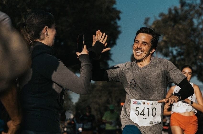 Wave One runner beaming as he high-fives a spectator near the finish, race bib 5410 on his chest