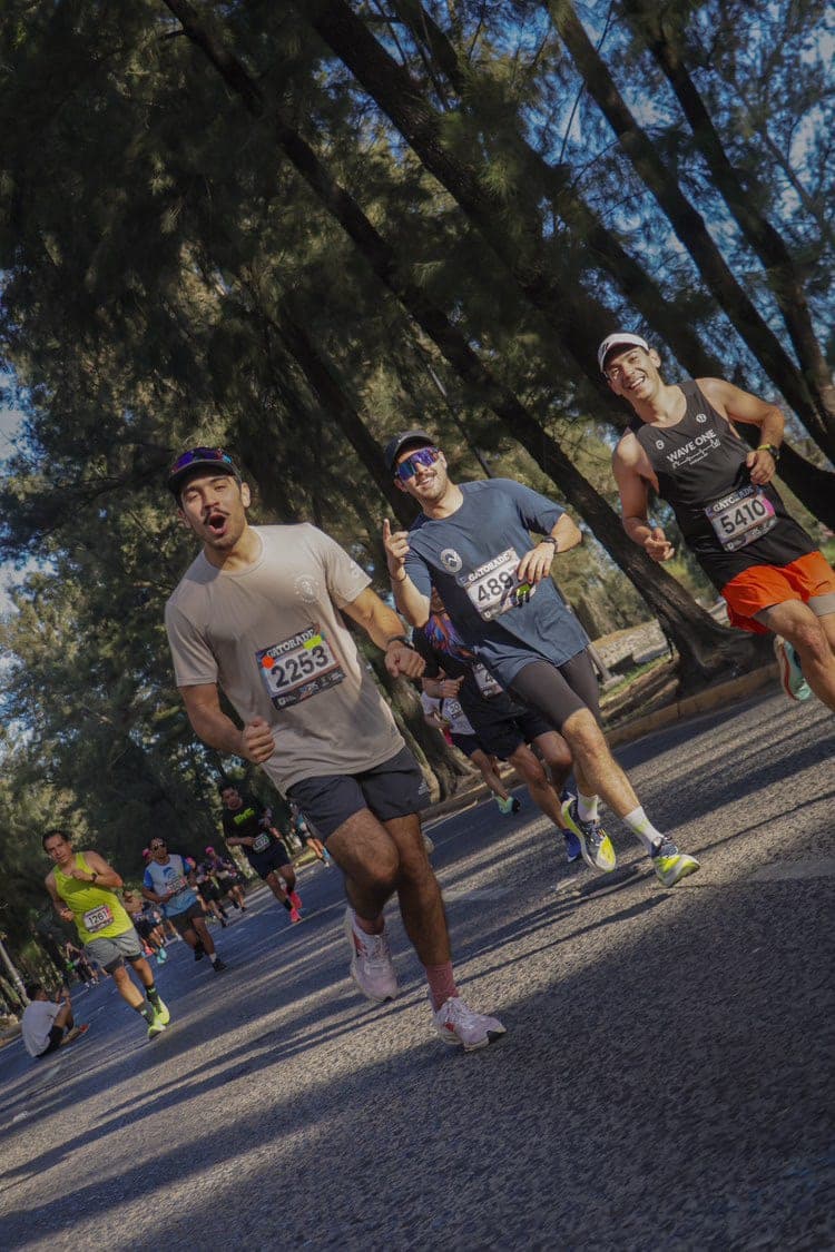 Three runners cruising under palm trees, the rear runner in a black Wave One singlet