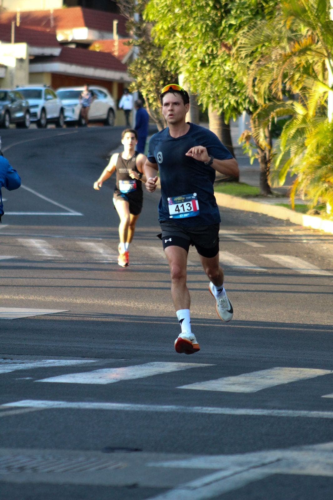 Lone runner pushing the pace down a quiet street at golden hour, palm trees on the right