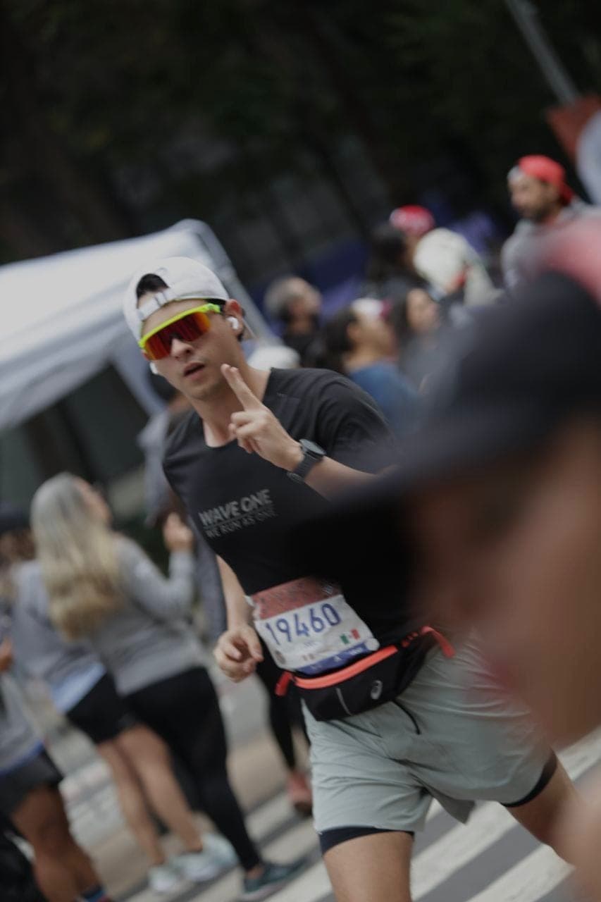 Wave One runner throwing up a peace sign mid-race in CDMX, bib 19460 in focus