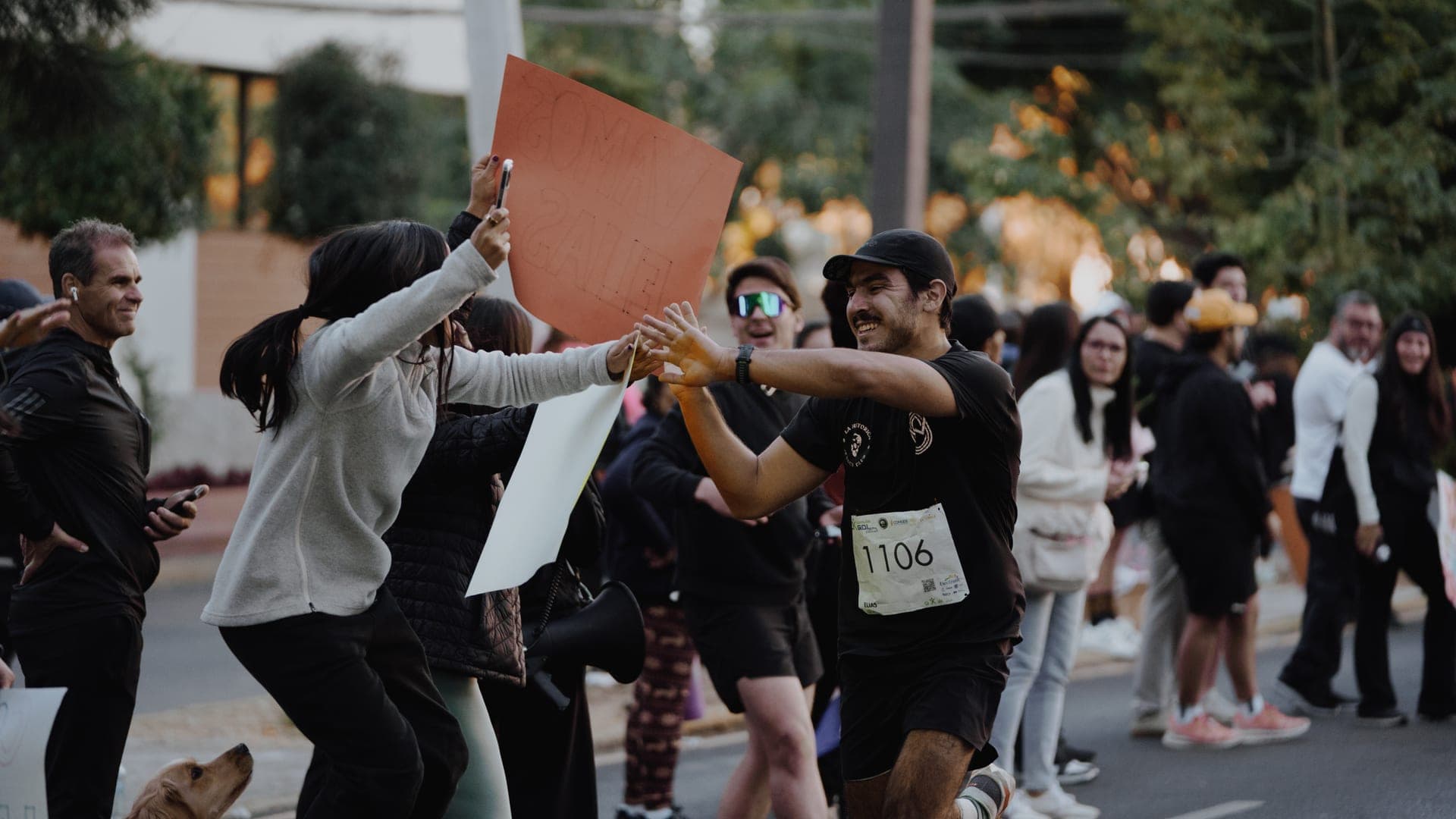 Runner high-fiving cheering Wavers holding handmade signs along the Primer Corte 21K course