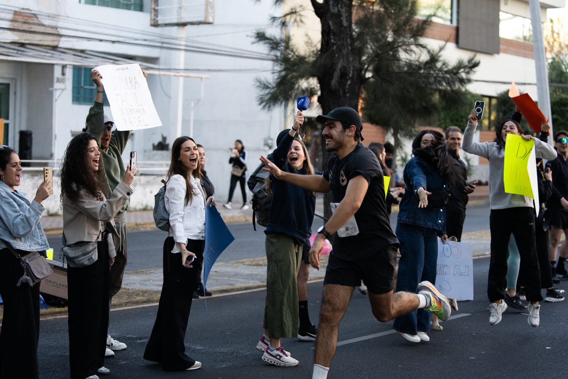 Wave One runner roaring past a cheering Guadalajara crowd waving signs at Primer Corte 21K
