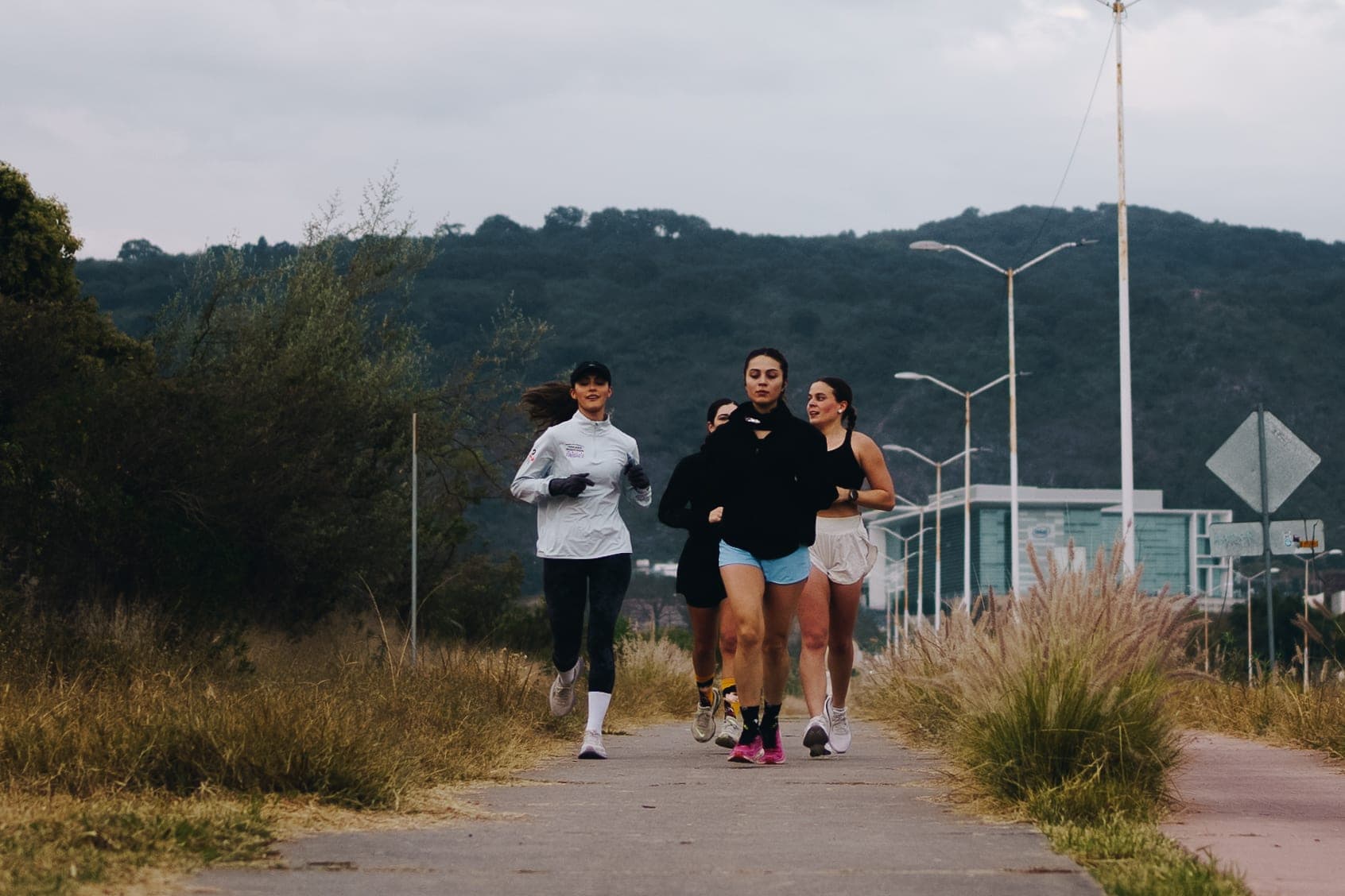 Wavers running side by side along a paved path with the Guadalajara hills rising behind