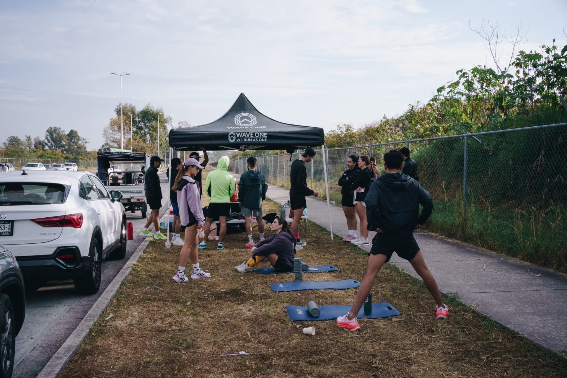 Wavers stretching and rolling out under a Wave One pop-up tent before a Saturday long run