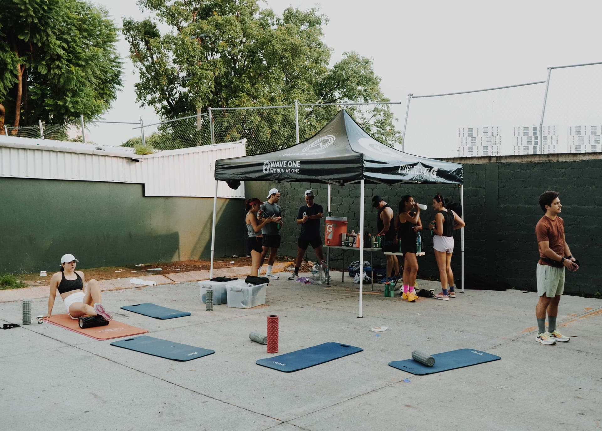 Wide shot of the Wave One tent with the squad warming up on yoga mats on a sunny morning