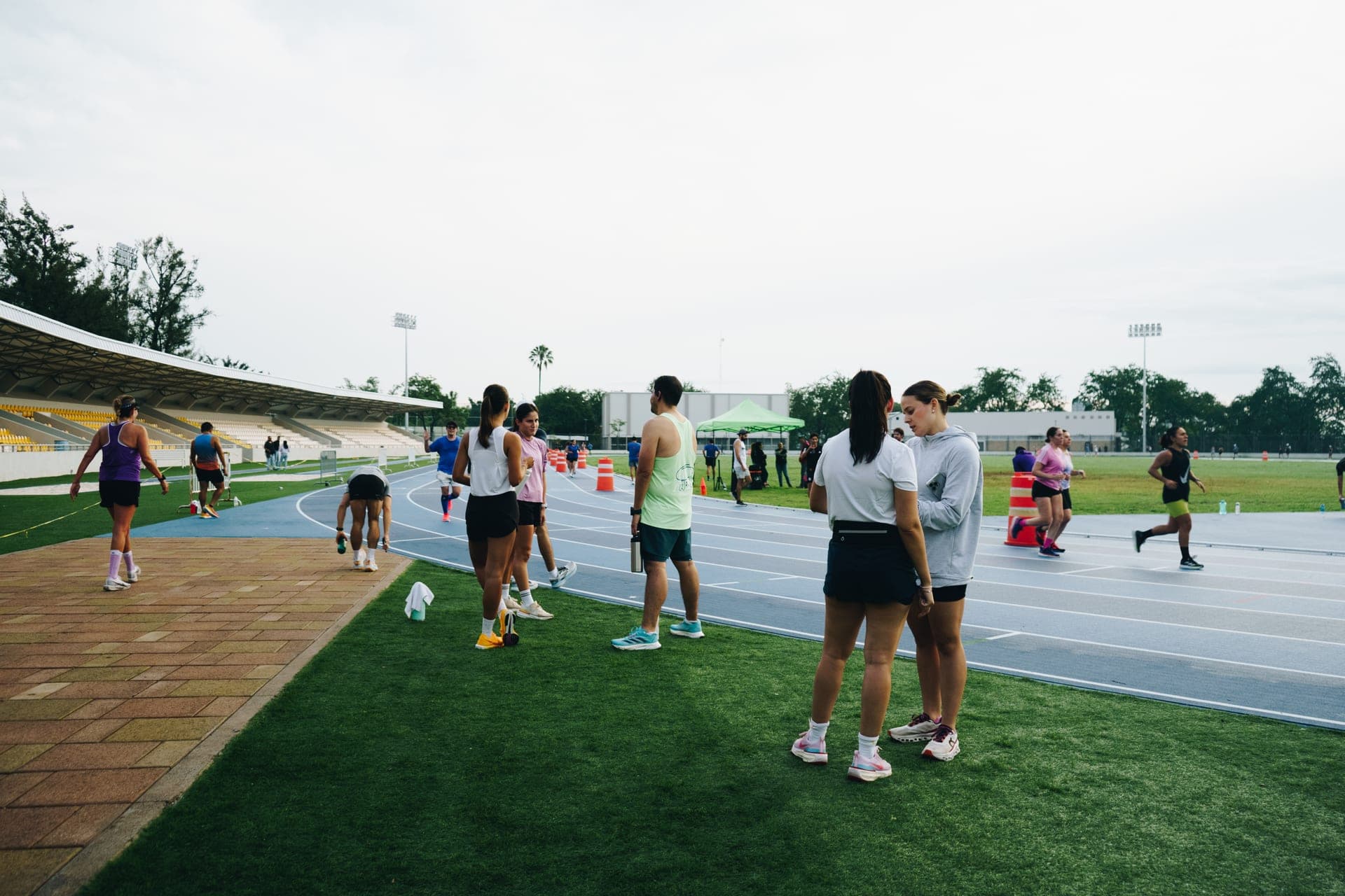 Wavers spread across the lanes of an empty stadium track at dusk, mid-warmup